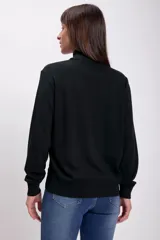 Polera negra de cuello alto y manga larga, confeccionada en tejido de punto.