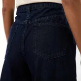 Jean de corte wide leg en color azul oscuro, con diseño de cinco bolsillos y costuras verticales decorativas en el frente. Presenta un tiro alto con cierre de botón y cremallera.