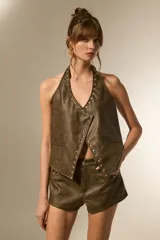 Top halter de eco-cuero color marrón verdoso, con escote en V profundo y bordes decorados con tachas plateadas.