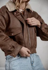 Campera de ecocuero color marrón, con forro interno de corderito sintético, cuello clásico, cierre frontal y bolsillos laterales.