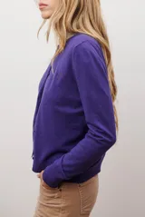 Cardigan azul de punto fino, con cuello redondo y cierre frontal de botones negros.