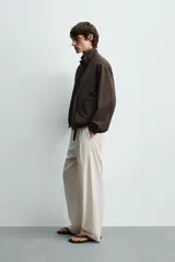 Cazadora bomber reversible de corte relaxed fit, color marrón oscuro, con cuello alto, cierre frontal de cremallera, bolsillos laterales de vivo y acabados elásticos en puños y dobladillo.