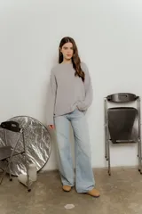 Sweater de punto con textura suave, color gris, de corte holgado, cuello redondo con terminación rulé y mangas largas con puños acanalados.