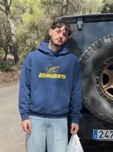 Hoodie azul marino con capucha, bolsillo frontal tipo canguro y estampado gráfico en el pecho con texto en amarillo.