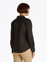 Camisa negra de popelín de mezcla de algodón elástico, corte regular, cuello inglés y puños con botón. Presenta el logo de Tommy Hilfiger bordado en el pecho.