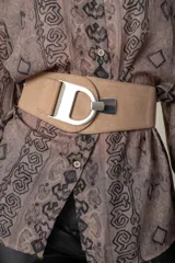 Cinto ancho marrón de cuero y elástico con hebilla metálica plateada con la letra D.