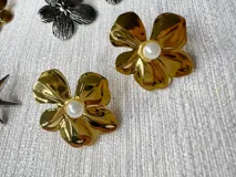 Caravanas de acero dorado en forma de flor con detalle de perla sintética en el centro.