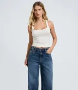 Pantalón wide leg de jeans azul oscuro, con cintura media y detalle de tachuelas metálicas a lo largo de las costuras laterales. Cuenta con bolsillos funcionales, trabillas para cinturón y cierre frontal con botón y cremallera.