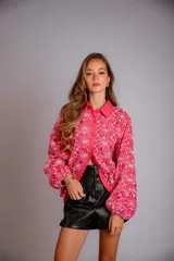 Camisa de manga larga con diseño abullonado, confeccionada en tela bordada con motivos florales. Presenta cierre frontal con botones y puños elásticos.