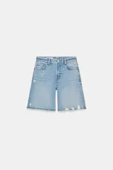 Bermudas de denim azul claro, tiro medio, corte ancho y largo hasta la rodilla. Presentan roturas y bordes deshilachados.