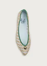 Bailarina de rejilla bordada con diseño de flores pequeñas en tonos beige y amarillo, con ribetes y talón en ante color verde. Presenta un detalle de media esfera metálica dorada en la puntera y suela plana.