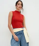 Blusa sin mangas de corte regular, confeccionada en una mezcla de algodón y modal, con cuello alto y diseño ajustado al cuerpo.