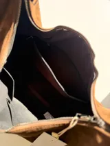 Cartera tipo hobo de diseño relajado, confeccionada en material con textura simil gamuza color chocolate. Presenta una silueta suave, cierre superior y asa corta combinada en simil cuero al tono.