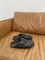 Zuecos de cuero marrón con diseño vintage, tachas plateadas y hebilla lateral.