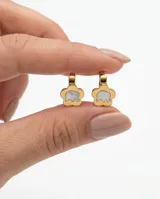Caravanas de acero dorado con diseño de flor que contiene un elefante en nácar en su interior.