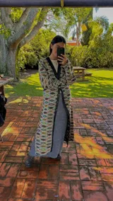 Vestido midi de silueta recta y diseño estampado, con escote en V profundo y detalles en contraste negro en el cuello y la botonera frontal. Cuenta con mangas largas y botones a lo largo de la prenda.
