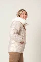 Campera puffer color crudo con brillo metalizado, con bolsillos delanteros, capucha con aplique de piel sintética desmontable y cierre frontal.