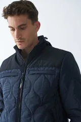 Campera de nylon azul marino para hombre con capucha, cierre frontal con cremallera, bolsillos laterales y frontales. El modelo usa talle M.