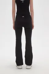 Calza flare de poliamida color negro, con diseño de tiro bajo y detalle de costura cruzada en la cintura.