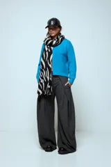 Cardigan corto de punto color rojo, con cierre frontal y cuello redondo. Presenta una textura acanalada y mangas largas.