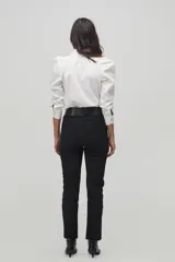 Camisa blanca de popelina de algodón con cuello camisero clásico, hombros abullonados, mangas largas y botones de nácar en el frente.