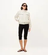 Campera rompeviento deportiva Get Over de microfibra, con estampado de lunares, cuello alto, cierre frontal oculto, bolsillos delanteros con ribete oscuro y puños elásticos.