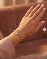 Pulsera de plata con baño de oro rose, con diseño rígido articulado y detalles centrales decorados con circnias pavé.