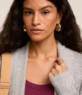 Cardigan alargado de punto color gris, con abertura frontal y bolsillos laterales.