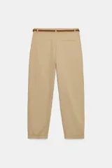 Pantalón chino color beige de tiro medio con bolsillos frontales y falsos bolsillos de vivo en la espalda. El bajo tiene un acabado con vuelta. Incluye un cinturón trenzado marrón.