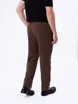 Traje slim color marrón de dos piezas, compuesto por un saco entallado de dos botones y un pantalón de corte recto. Confeccionado en mezcla de lana y poliéster.