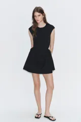 Vestido corto negro confeccionado en 100% algodón, de cuello redondo y mangas cortas. Presenta detalle de lazadas en los laterales de la cintura y falda con vuelo.