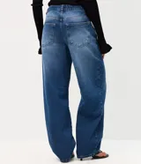 Pantalón baggy de jean azul con tiro medio, corte holgado, recortes en las rodillas y llavero decorativo con perlas y dije de corazón.
