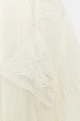 Blusa blanca de manga larga y escote en V, con detalles de crochet en el pecho y puños.