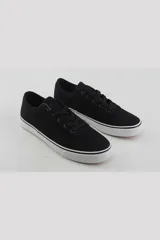 Championes urbanos de lona color negro con suela de goma blanca y detalle de línea negra en el borde.