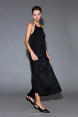 Vestido largo negro de lurex, con escote halter y diseño fluido y acampanado.