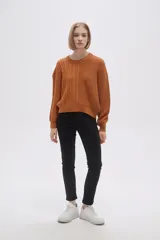 Sweater de tejido de punto color verde oliva, con cuello redondo y manga larga. Presenta un diseño de punto trenzado en el frente y mangas, contrastando con un tejido acanalado liso en el lado derecho del torso.