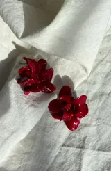 Caravanas artesanales en forma de flor, realizadas en porcelana con acabado brillante en color rojo intenso.