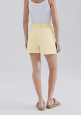 Short de lino en color crudo, de corte recto y tiro medio. Presenta una cintura con pasacintos y un cordón trenzado decorativo con borlas en el frente.