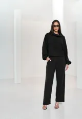 Pantalón de tricot negro de corte recto y tiro alto, con cintura elástica y bolsillos laterales. Presenta una textura sutil en el tejido y una caída fluida.