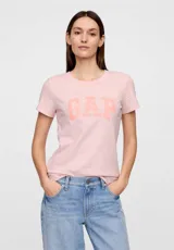 Remera de algodón color rosa claro, con cuello redondo, mangas cortas y logo de la marca estampado en el frente en un tono más oscuro.