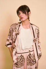 Camisa de manga corta color rosado con estampado barroco en tonos marrones, cuello camisero y cierre frontal de botones.