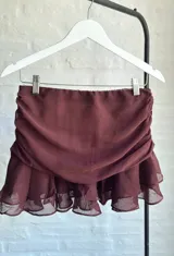 Minifalda marrón de tul con frunces laterales y volados en el ruedo.