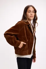 Campera de terciopelo color marrón chocolate, con cierre frontal, bolsillos laterales y elástico en el ruedo. Presenta un diseño de corte holgado con costuras marcadas.