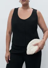 Chaleco negro de corte recto y estilo sastre, con cuello redondo abierto, tirantes anchos y cierre frontal de botones. Cuenta con forro interior completo.