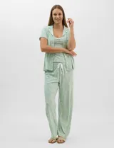 Set de pijama de tres piezas en color verde menta con estampado floral sutil, compuesto por una camisa de manga corta con botones, una musculosa básica y un pantalón largo de corte recto con cordón ajustable en la cintura.