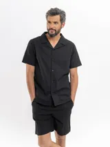 Camisa de manga corta color negro con sutil patrón tipo damero, cuello cubano y cierre frontal con botones.