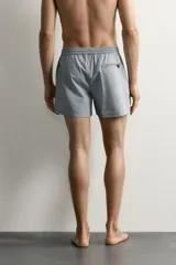Short de baño confeccionado en tejido técnico con patrón de rayas verticales en tonos azul marino y blanco, con cintura elástica ajustable mediante cordón y bolsillos laterales.