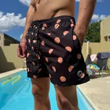 Short de baño negro con estampado de rodajas de naranja, cintura elástica con cordón ajustable y logo circular en el ruedo.