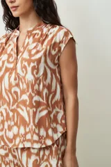 Blusa negra sin mangas, con cuello mao y abertura frontal con botones. Presenta frunces en la zona de los hombros, dándole un calce holgado.