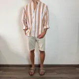 Camisa de manga larga con cuello mao, confeccionada en tejido de lino a rayas verticales en tonos blanco y celeste. Presenta cierre frontal con botones y corte clásico.